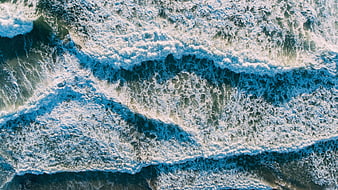 Aerial view of crashing ocean waves with white foam