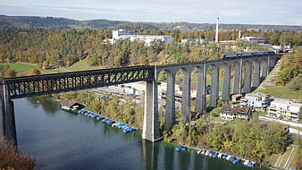 Train crossing stone viaduct over river in autumn landscape