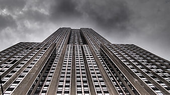 Low angle view of brutalist skyscraper against cloudy sky