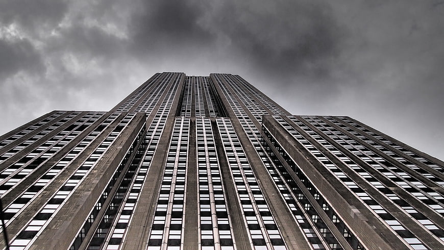 Low angle view of brutalist skyscraper against cloudy sky