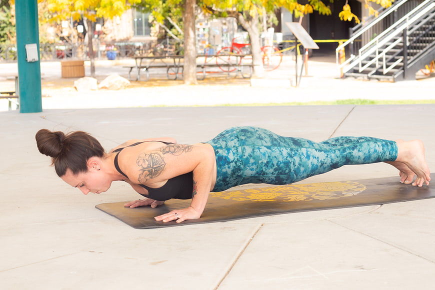 Woman doing plank exercise on yoga mat outdoors