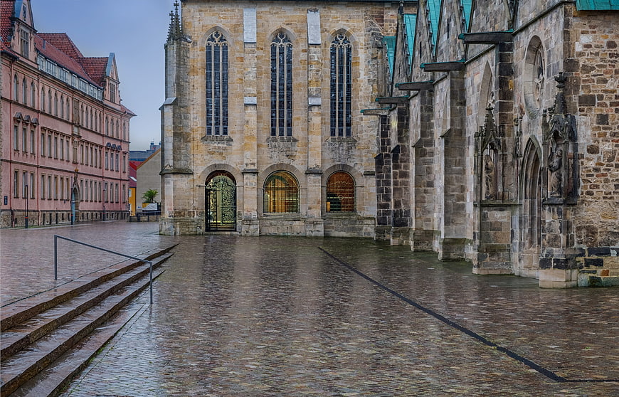 Wet cobblestone square with historic church and pink building