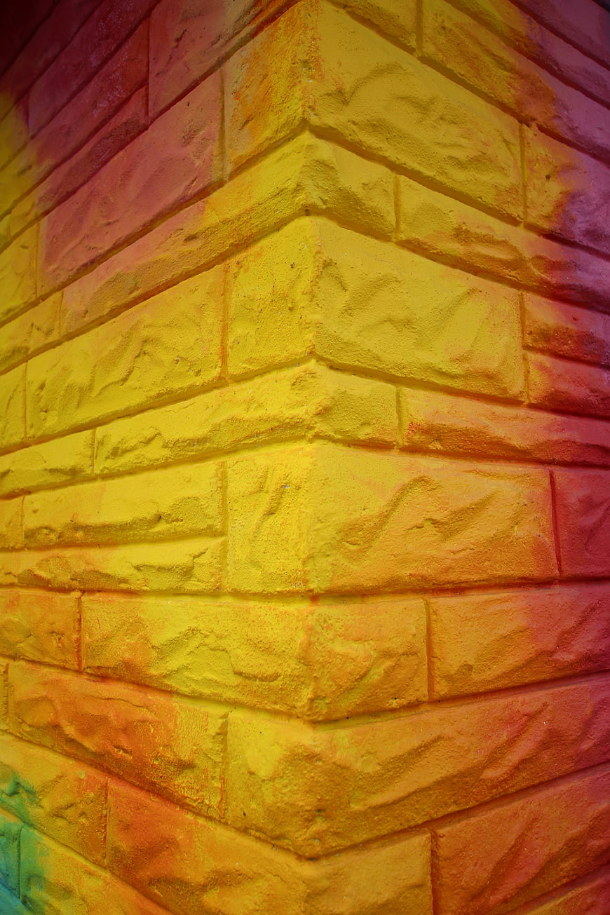 Colorful Painted Brick Wall Corner with Vibrant Yellow and Red Hues