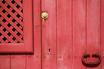 Close-up of a vibrant red wooden door with vintage lock and handle