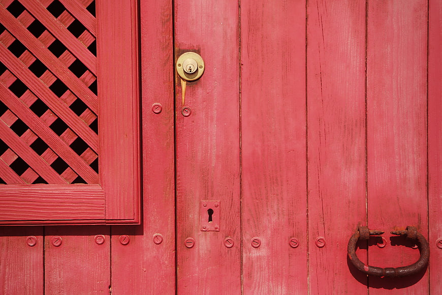 Close-up of a vibrant red wooden door with vintage lock and handle