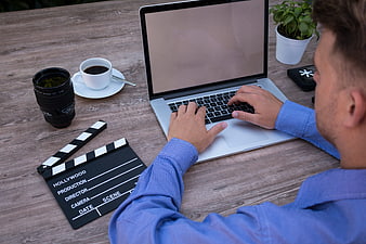 Filmmaker working on laptop with clapperboard and coffee