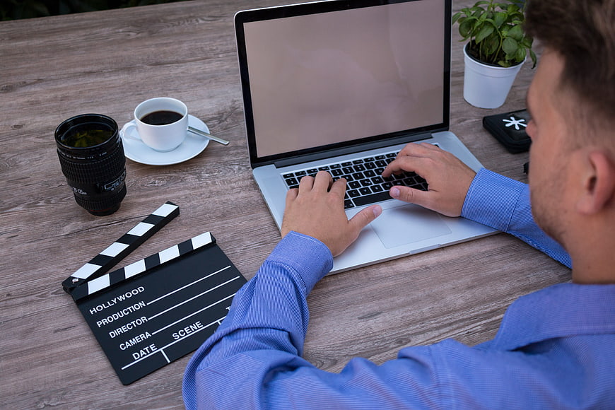 Filmmaker working on laptop with clapperboard and coffee