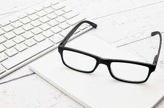 Black Reading Glasses on White Notebook and Keyboard