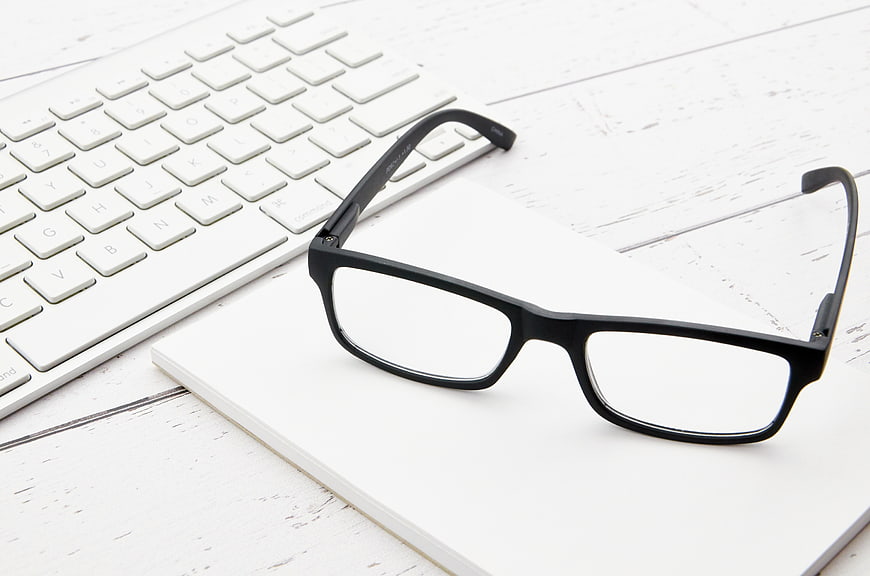 Black Reading Glasses on White Notebook and Keyboard