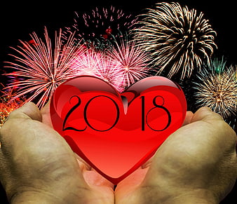 Hands holding red heart with 2018 and fireworks background