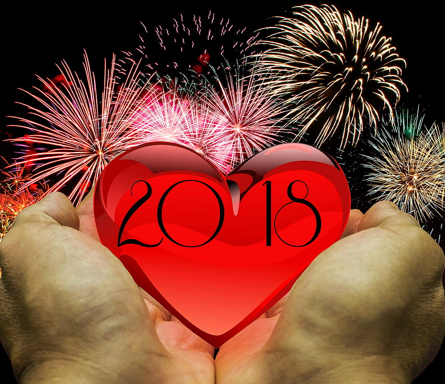 Hands holding red heart with 2018 and fireworks background