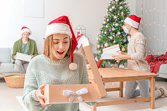 Happy woman opening Christmas gift box with family in background