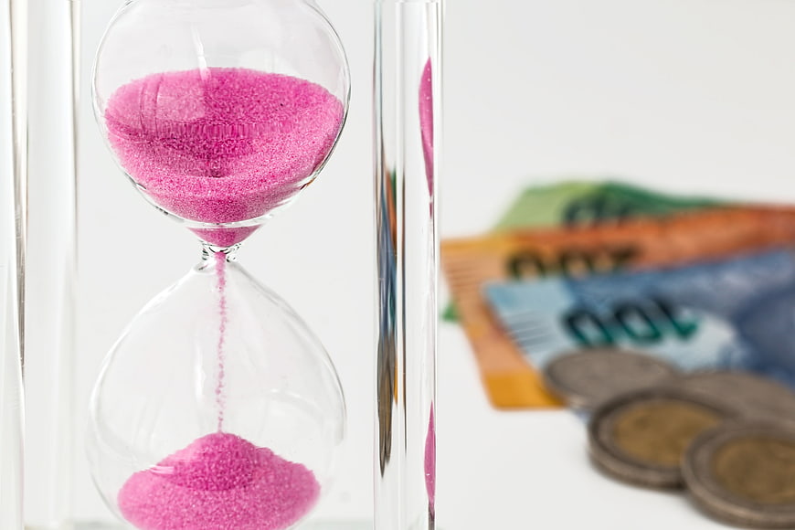 Pink hourglass with Australian currency in background
