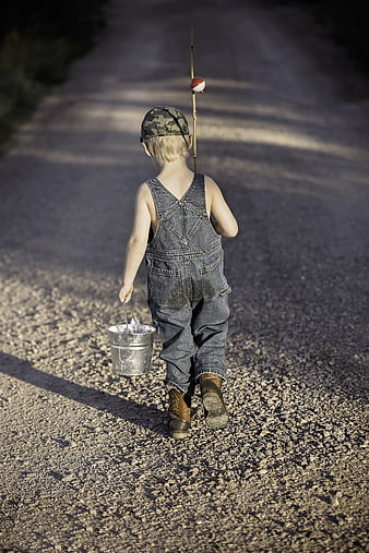 Little boy walking away with fishing bucket and stick