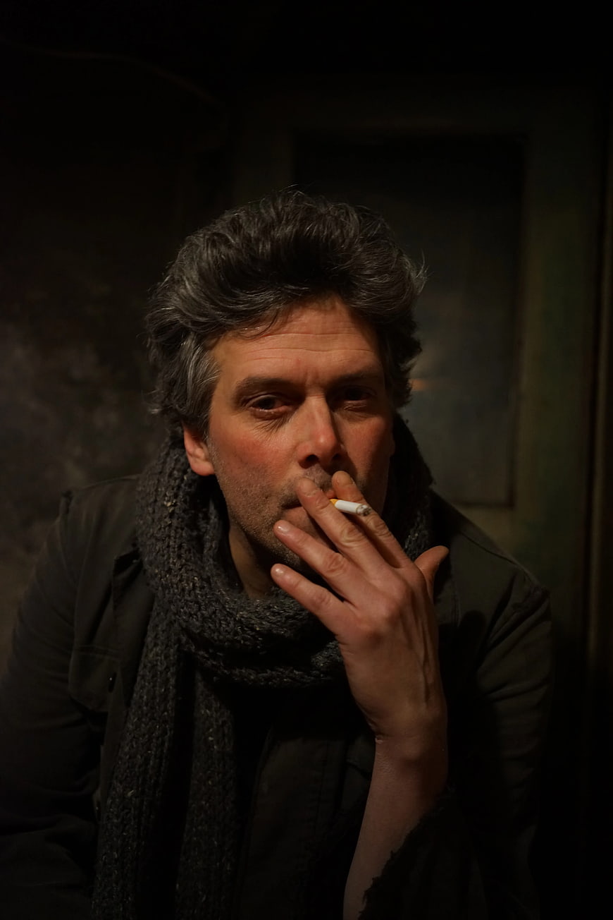 Moody Portrait of Man Smoking Cigarette in Dark Room