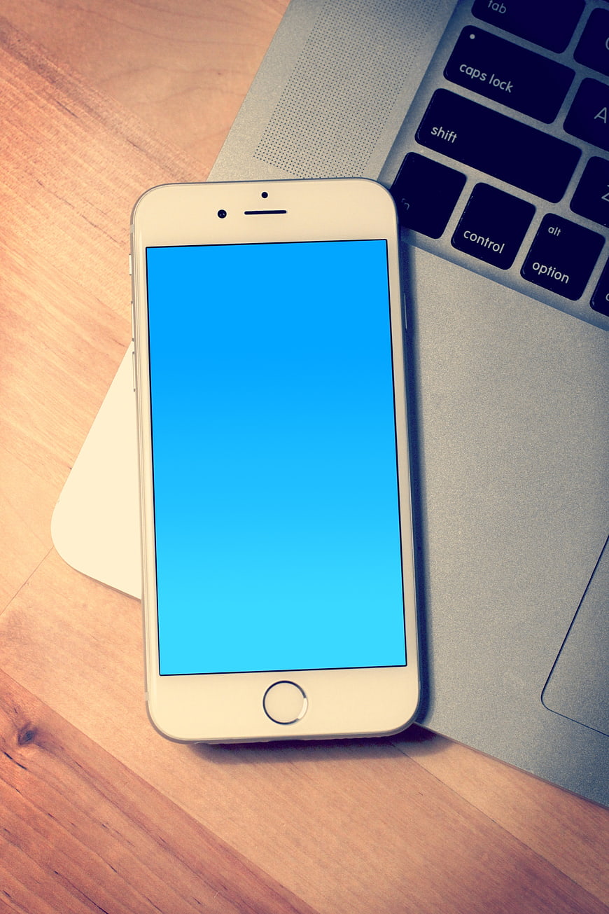 White Smartphone with Blue Screen on Laptop Keyboard