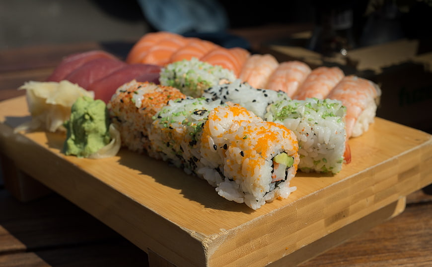 Assorted sushi platter on wooden board with wasabi and ginger