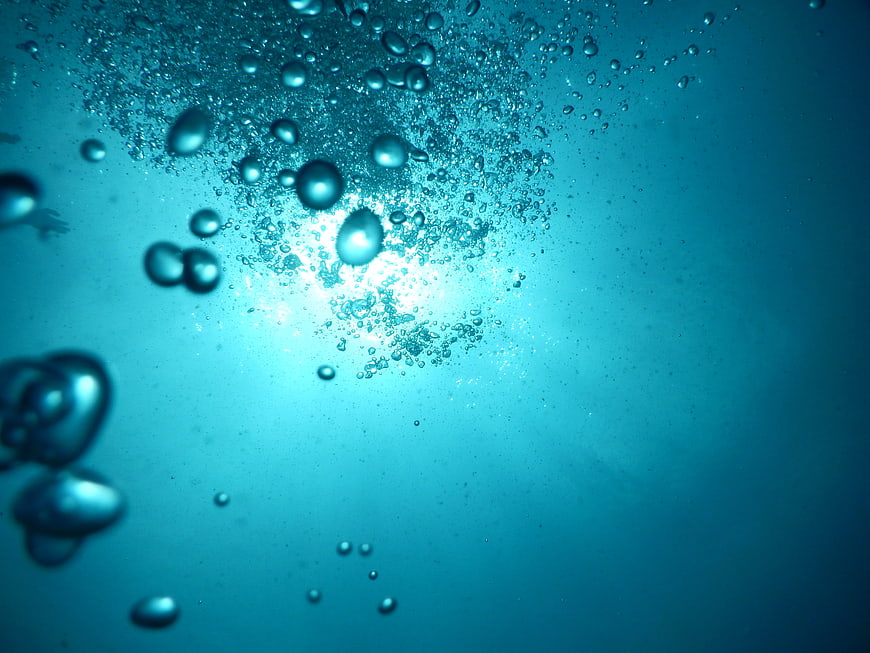 Underwater air bubbles rising through deep blue ocean water