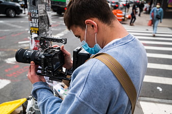 Videographer Filming on Busy City Street with Professional Camera