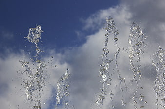Water fountain spray against blue sky with clouds