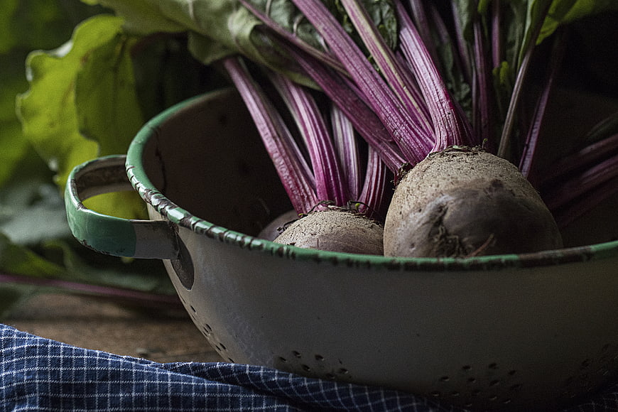 Fresh raw beets with leaves in vintage colander