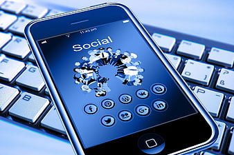 Smartphone displaying social media icons on a laptop keyboard
