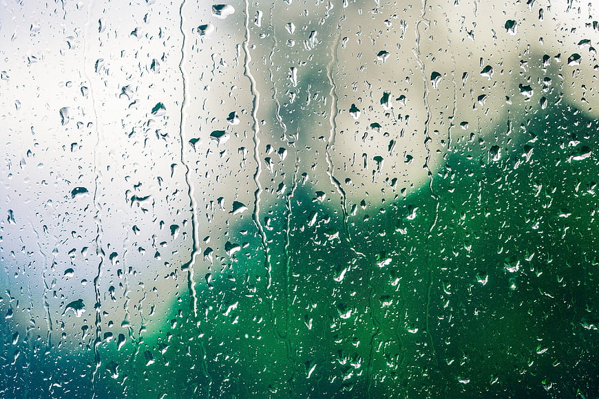 Raindrops on Glass Window with Blurred Green Background