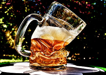 Bent Glass Beer Mug With Amber Liquid On Outdoor Table