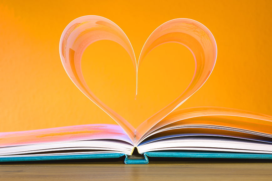 Open Book Pages Bent into Heart Shape on Orange Background
