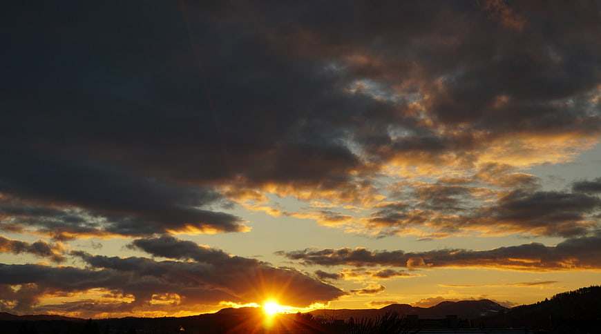 Dramatic sunset with golden clouds over mountain silhouette