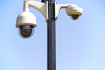 Dual Security Cameras on Pole Against Blue Sky