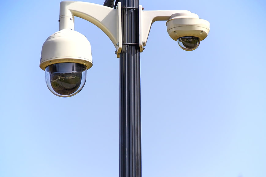 Dual Security Cameras on Pole Against Blue Sky