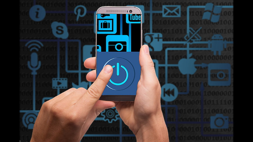 Hands holding smartphone with power button and digital technology background