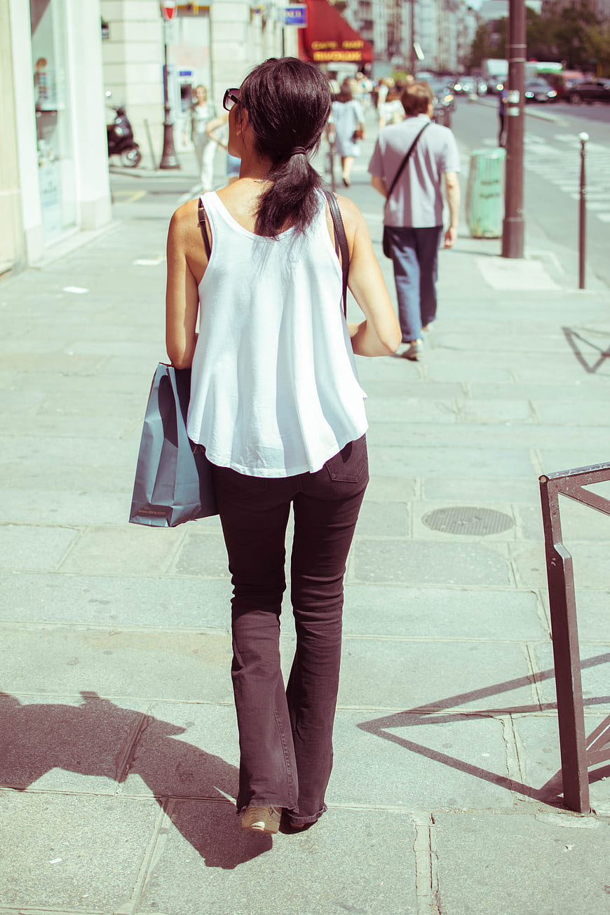 Woman Walking Away on City Sidewalk with Shopping Bags