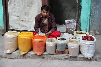 Indian Spice Vendor Sitting with Colorful Sacks of Spices
