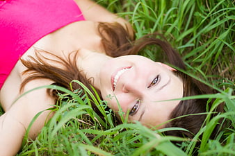 Smiling Brunette Woman Lying in Green Grass
