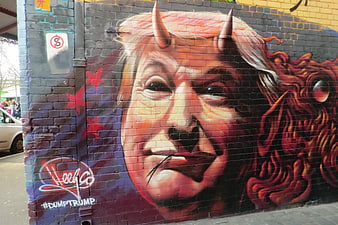 Political graffiti mural of Donald Trump with devil horns