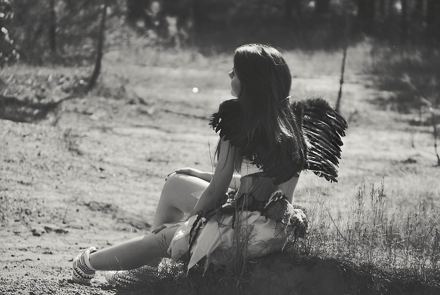 Black and white portrait of girl with angel wings in forest