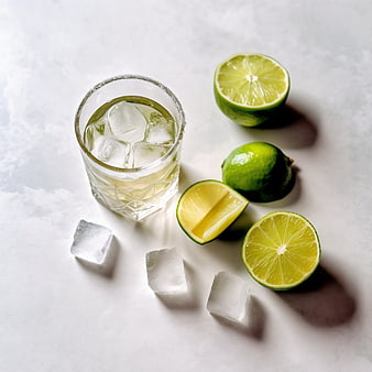 Tequila cocktail with ice and fresh limes on white background