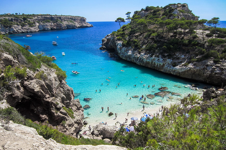Aerial view of turquoise bay with cliffs and swimmers in Mallorca