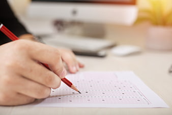 Student Filling Out OMR Exam Sheet With Red Pencil
