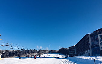 Ski resort with chairlifts and hotel under blue sky
