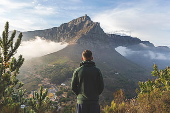 Man Looking at Majestic Mountain Peak with Clouds