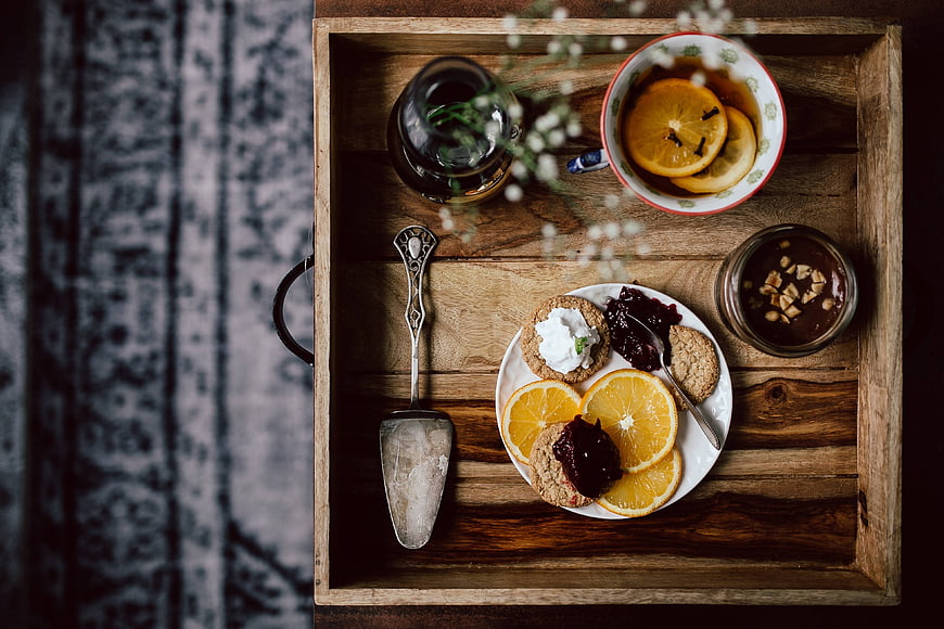 Top view of rustic breakfast tray with cookies, tea, and oranges
