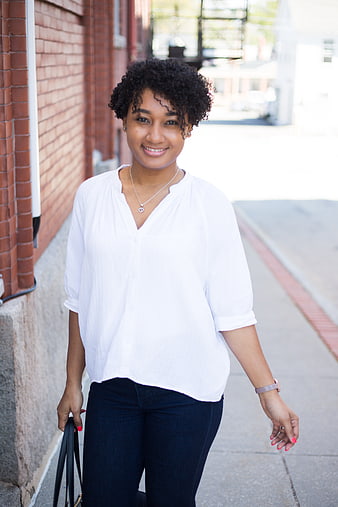 Smiling young woman walking on city sidewalk