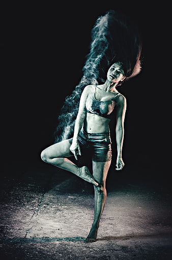 Female dancer performing dynamic pose with dramatic powder explosion