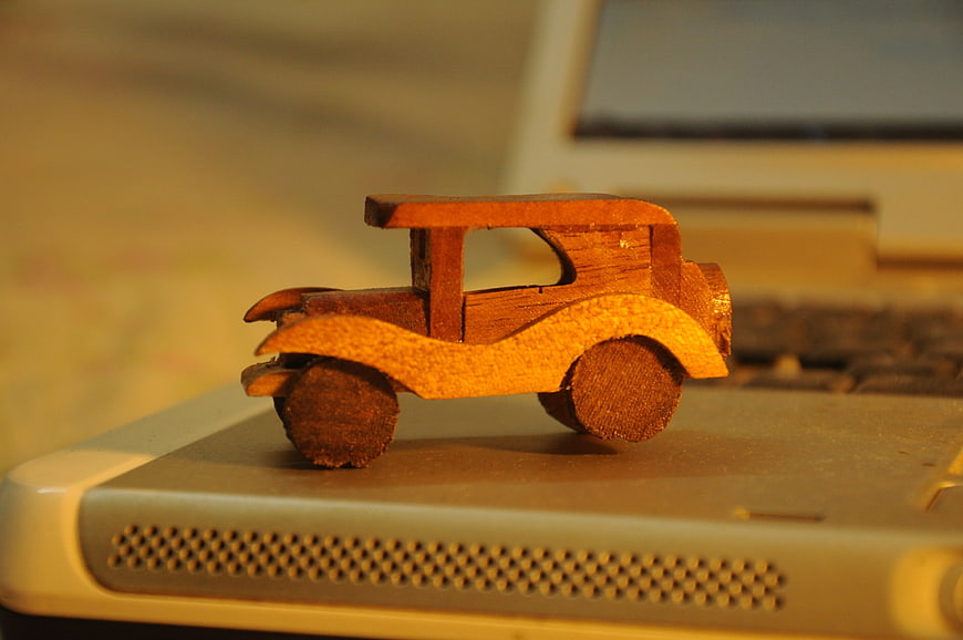 Handcrafted wooden toy car on laptop keyboard