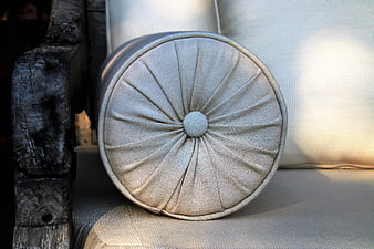 Close-up of beige cylindrical cushion on rustic wooden chair