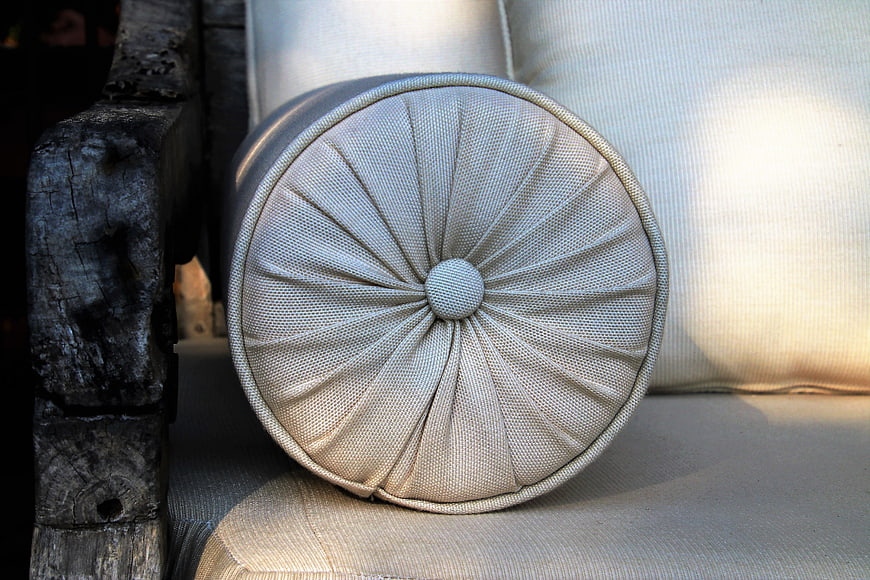 Close-up of beige cylindrical cushion on rustic wooden chair