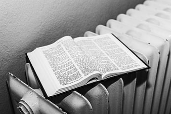 Open Bible resting on vintage radiator in black and white
